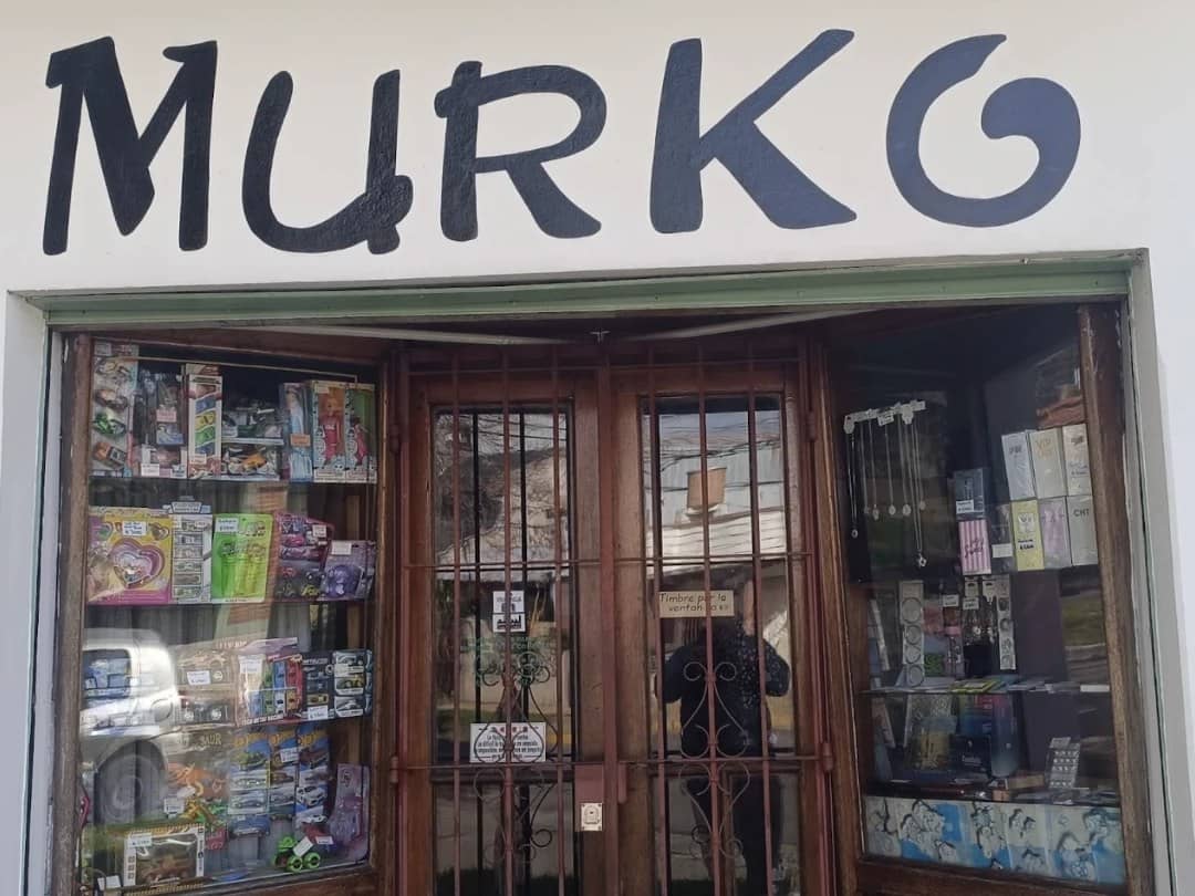 La esquina de Murko: fachada blanca con MURKO pintado a mano, LIBRERIA y REGALERIA en las columnas, vidrieras con juguetes y bijouterie, y el cartel de HOP.