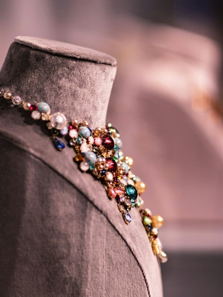 Foto de referencia: un collar de bijouterie con piedras de colores en un busto de exhibición.